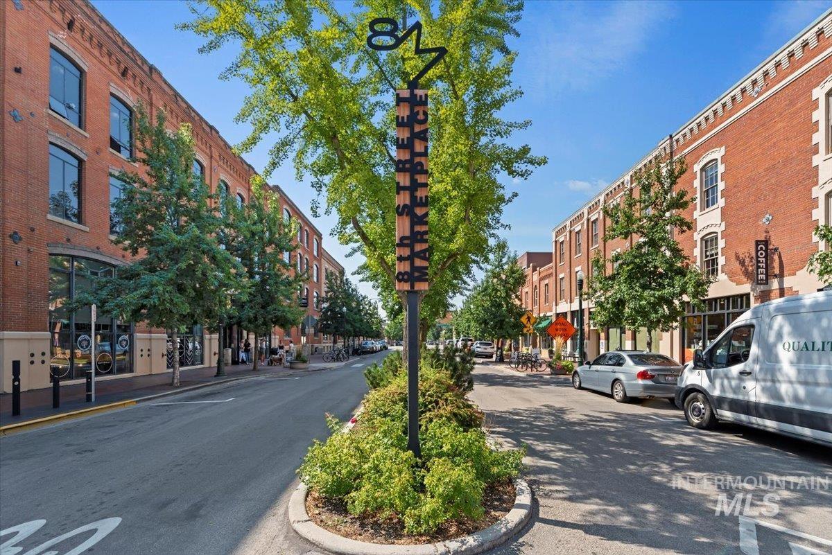 View of asphalt street featuring curbs, street lights, and sidewalks