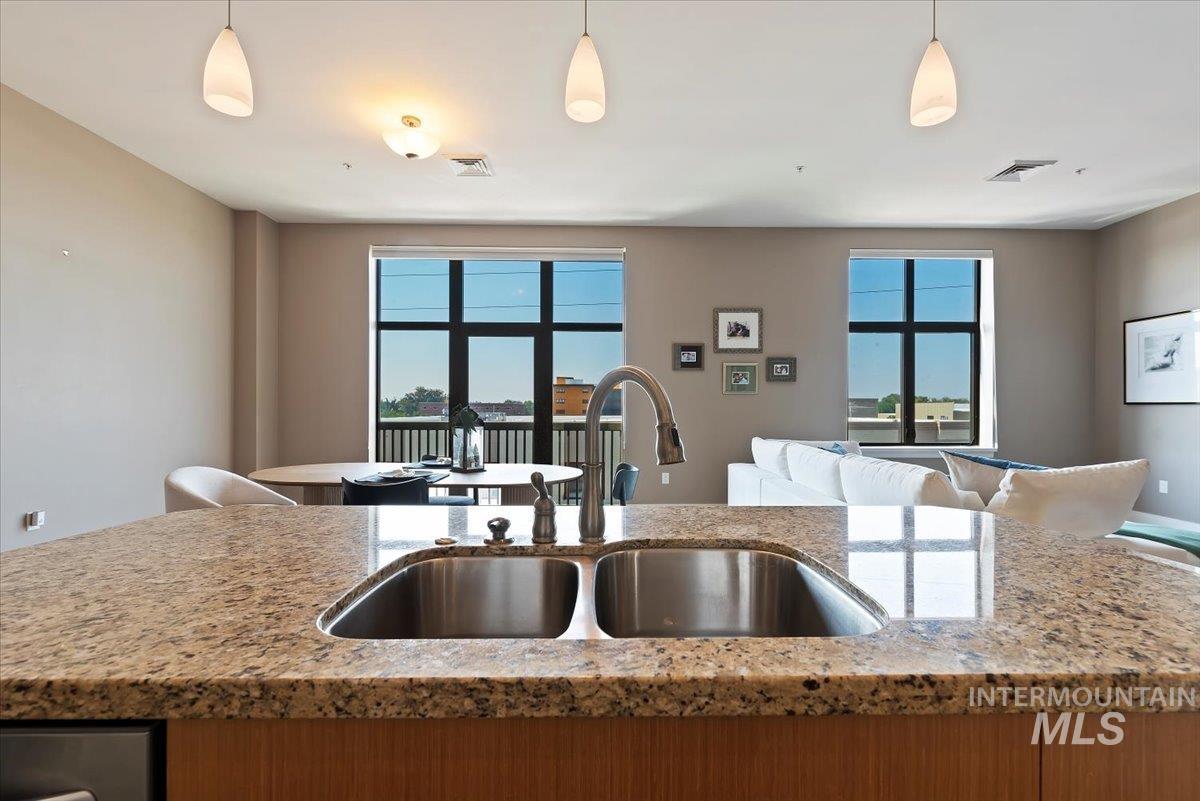 Kitchen featuring light stone counters, decorative light fixtures, and open floor plan