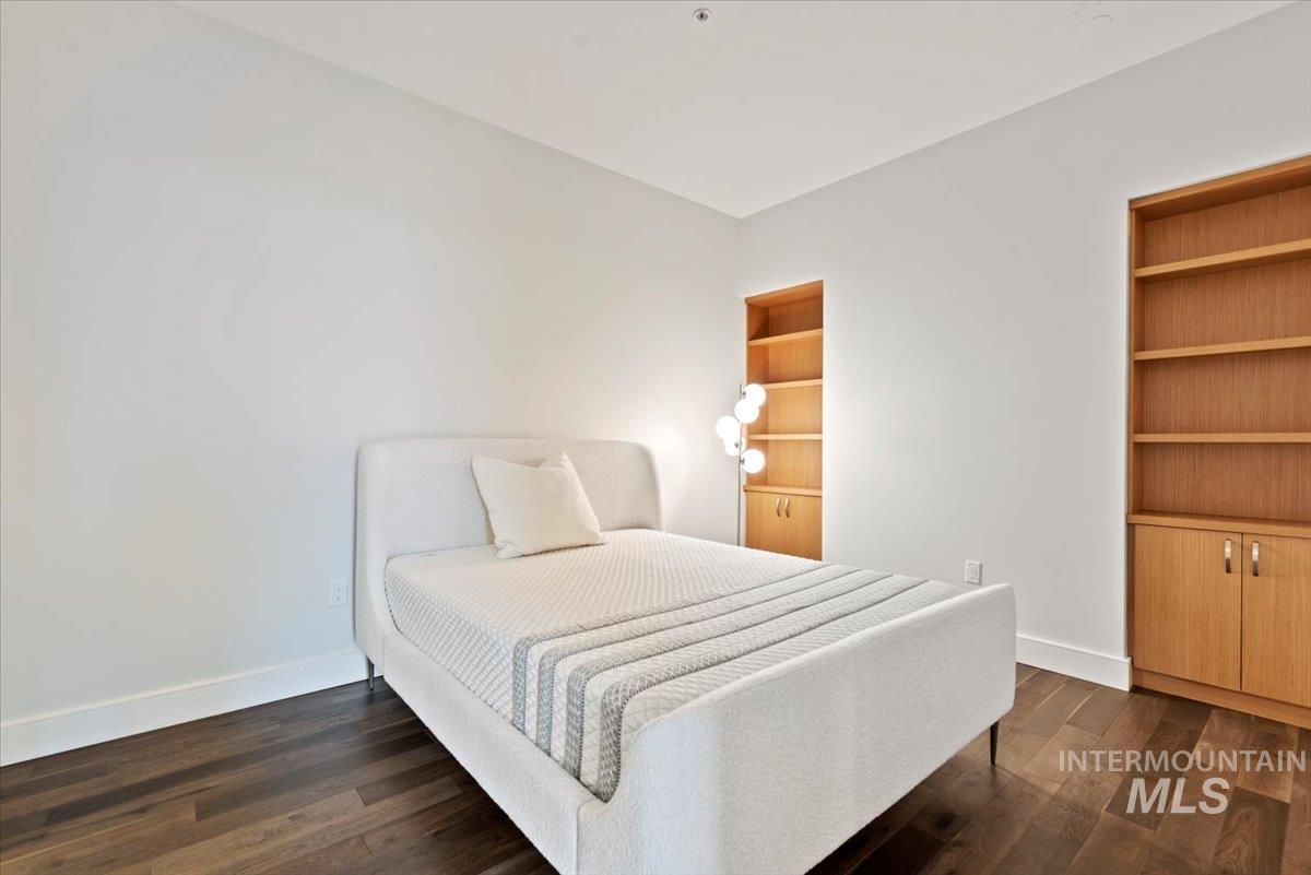 Bedroom with baseboards and dark wood-style flooring