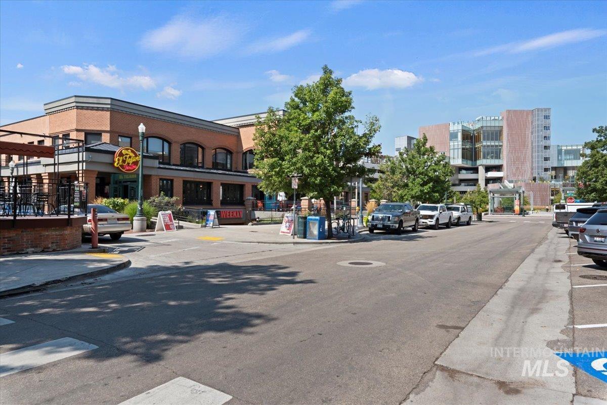View of asphalt street with traffic signs, curbs, sidewalks, and street lighting
