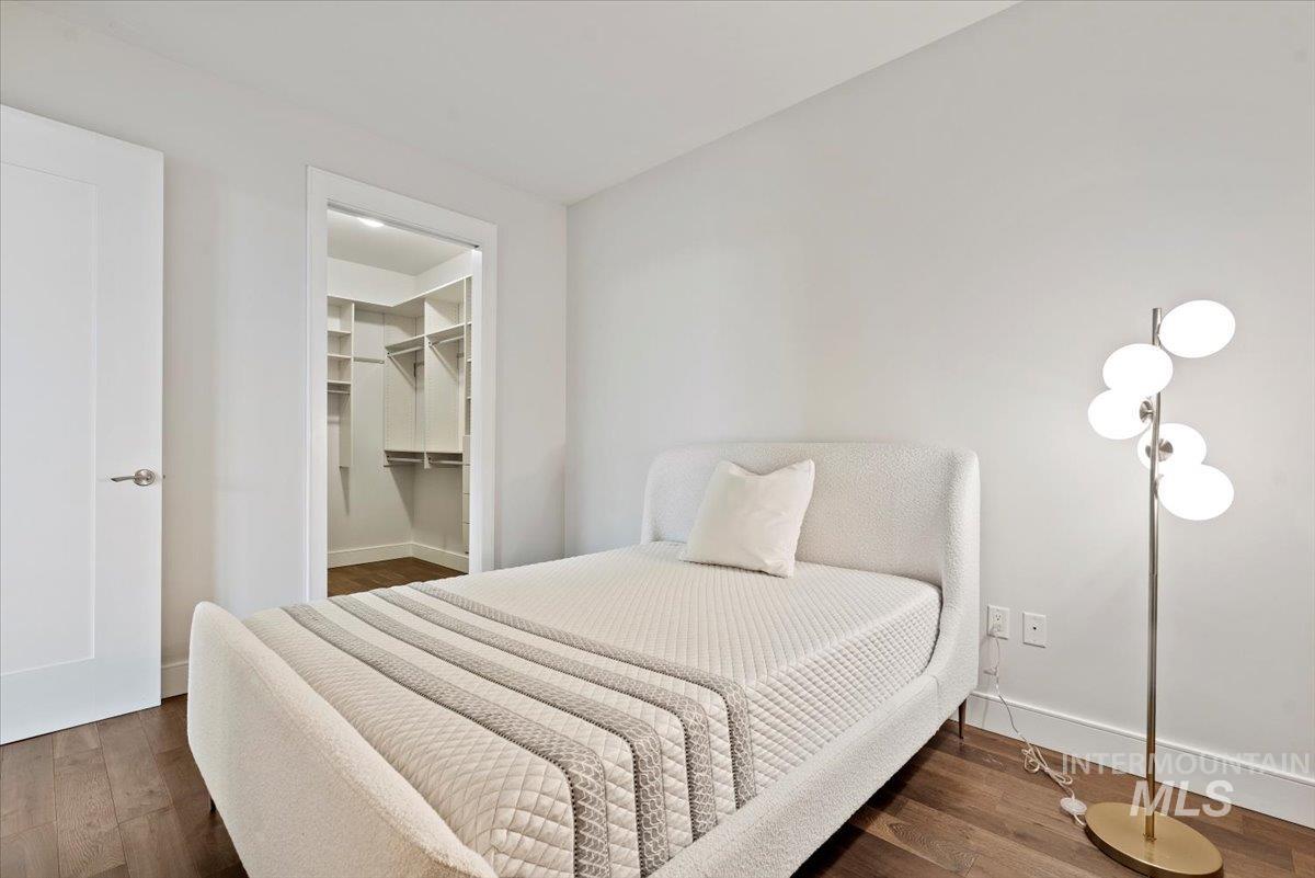 Bedroom with dark wood-type flooring and a spacious closet