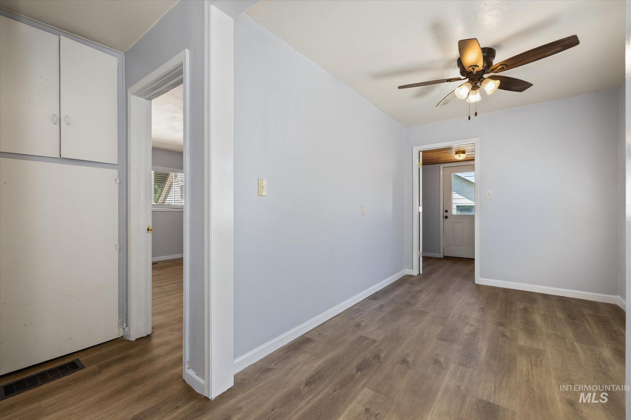 Interior room featuring wood-finish flooring, light blue wall paint, and white baseboards