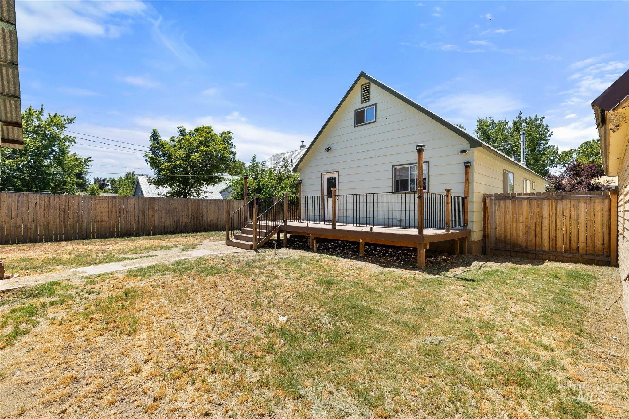 Expansive outdoor deck with railing and stairs, situated against the rear exterior of the property