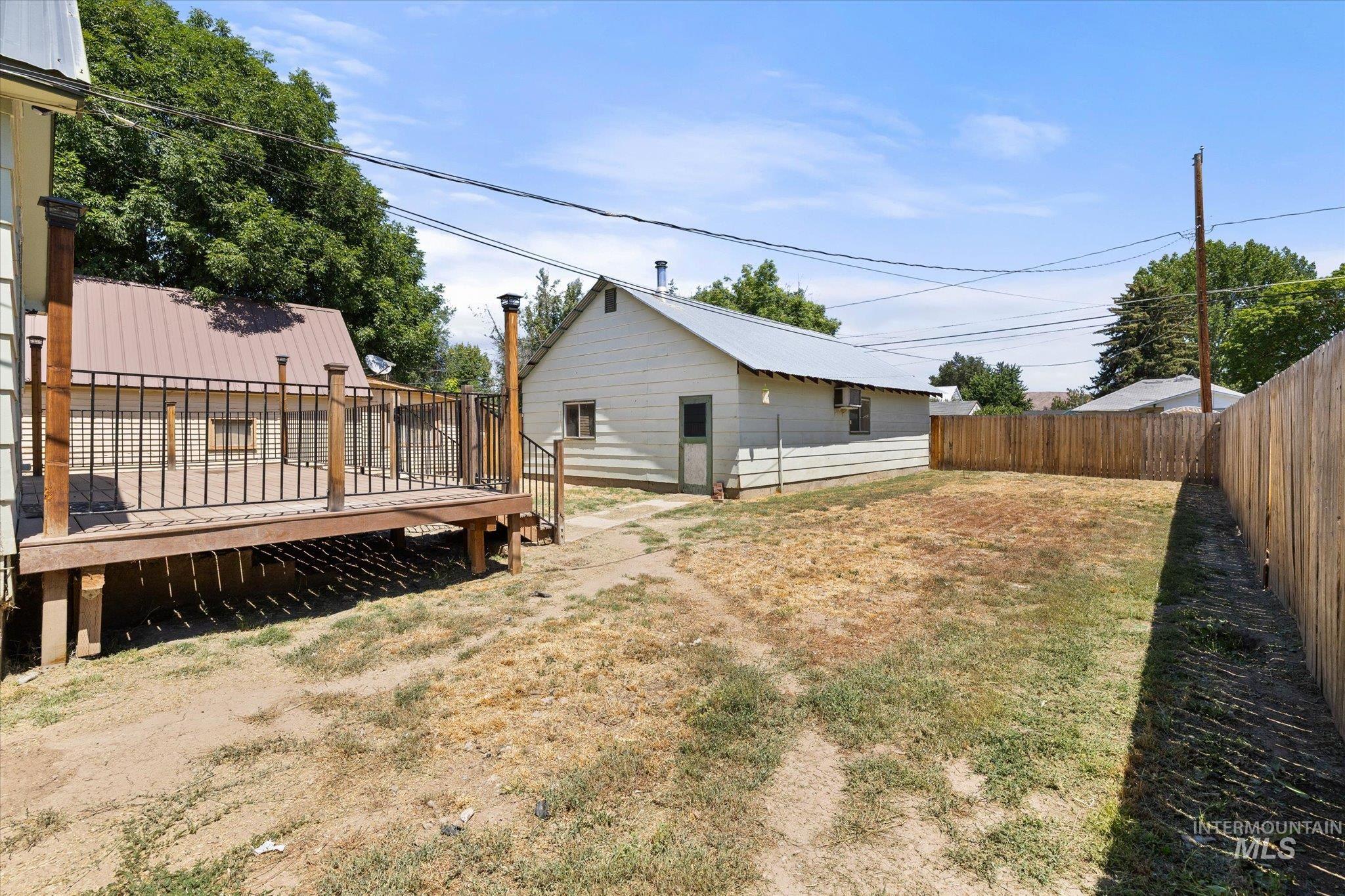 Private outdoor deck with wood posts and dark metal railing, offering a direct entrance to an additional structure with a metal roof