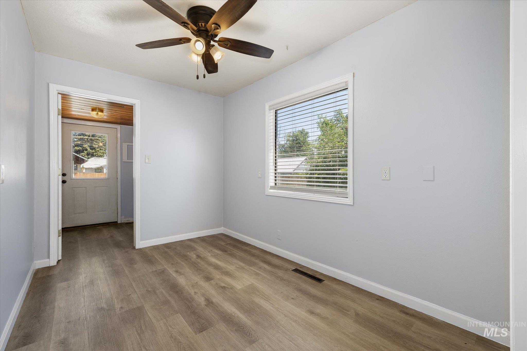 Room featuring wood-finish flooring, light blue wall paint, and a ceiling fan with integrated lighting