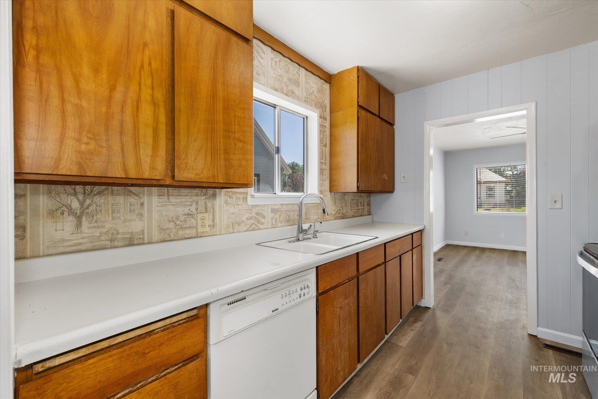 Kitchen featuring wood cabinetry, white countertops, a double basin sink with a chrome faucet, and a built-in dishwasher