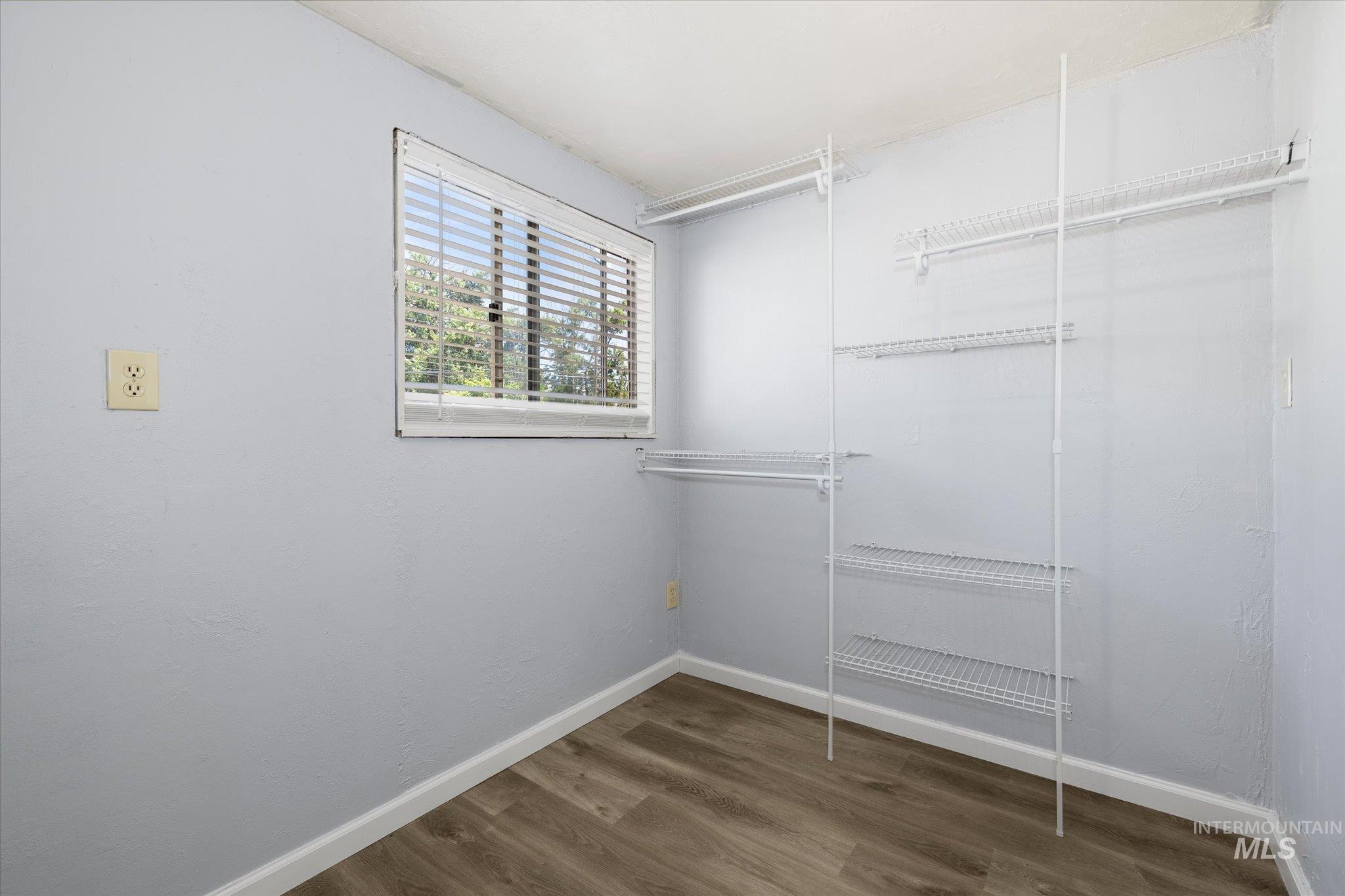 Interior room with wood-finish flooring, light blue walls, and white baseboards