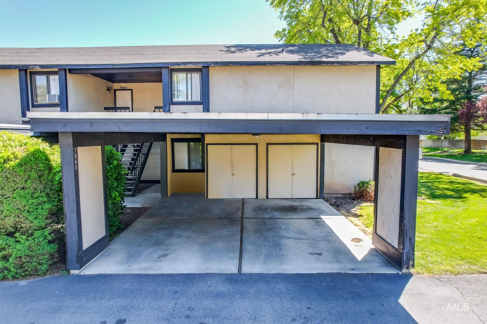 View of front of property featuring stairs, stucco siding, and a carport