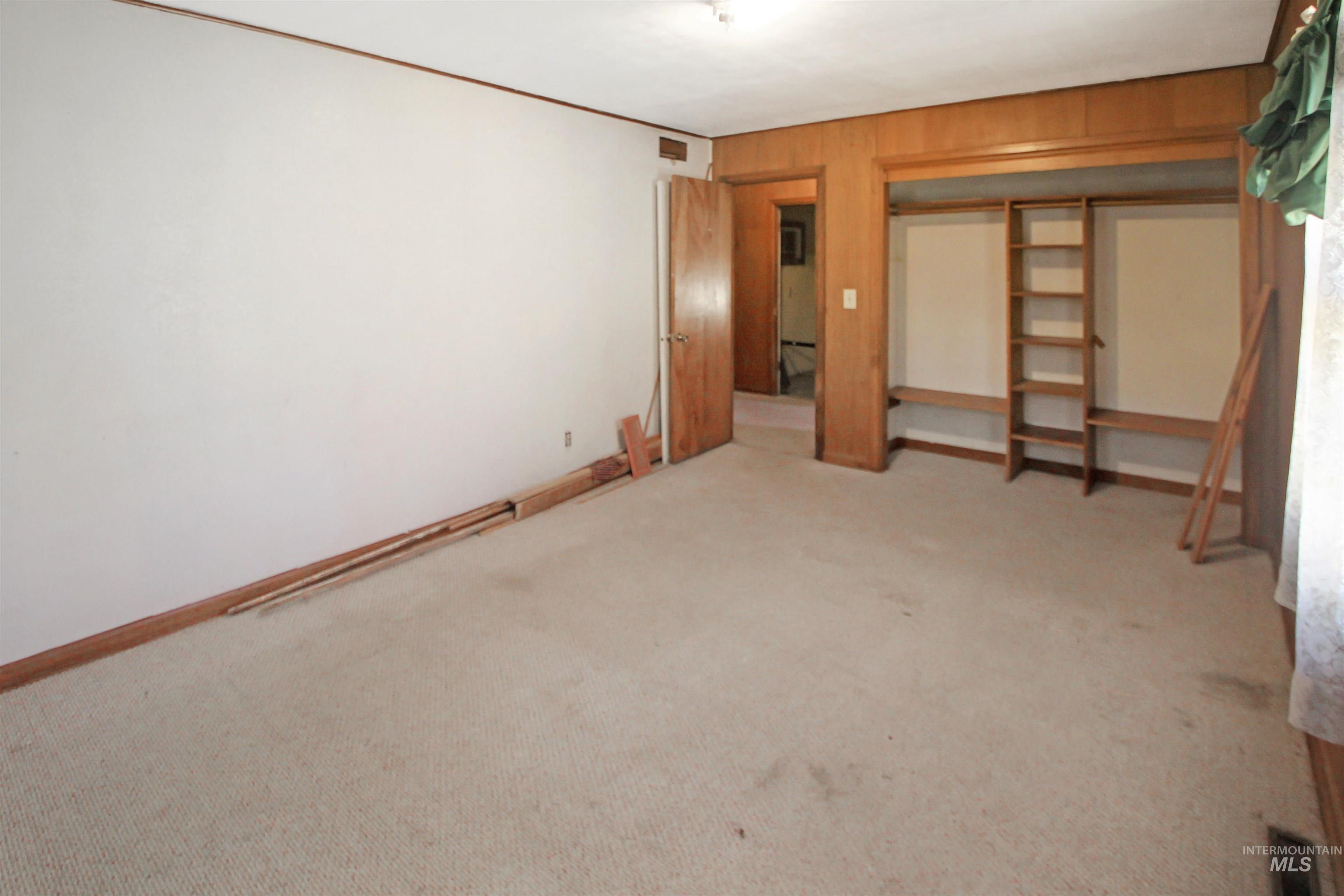 Unfurnished bedroom featuring wooden walls, a closet, and carpet
