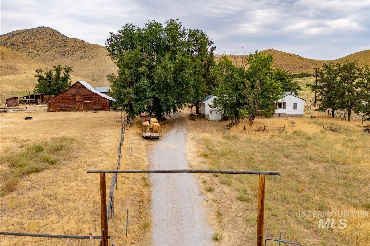 View of front of property with a view of countryside, a mountain view, an outbuilding, and driveway