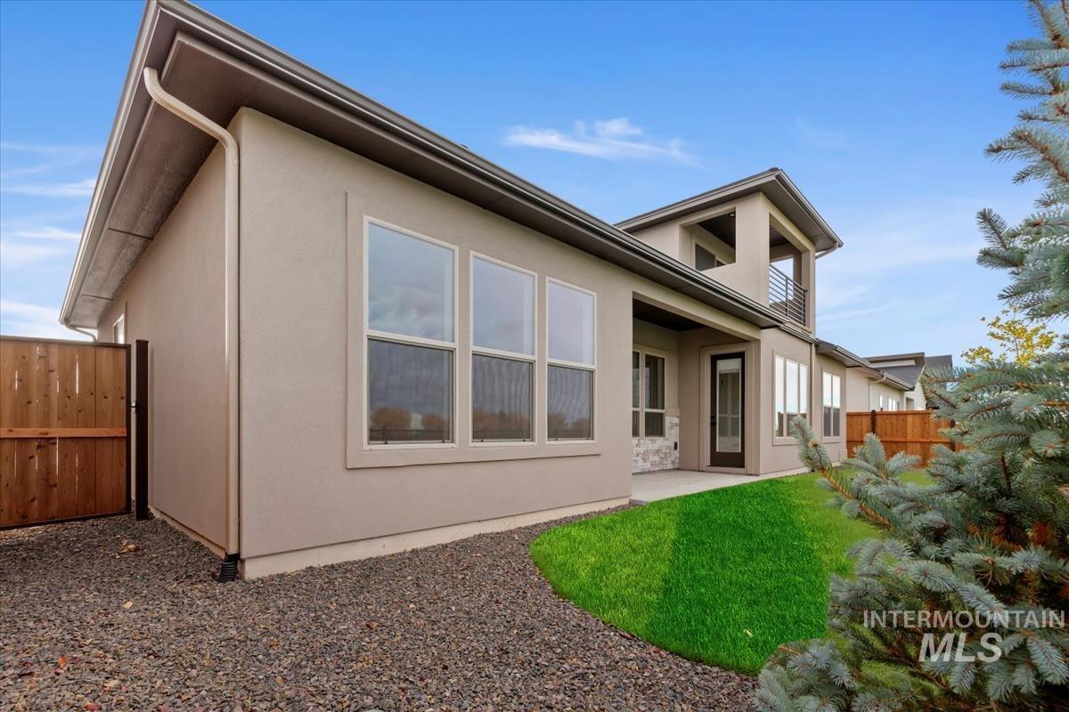 Rear view of property with a patio, stucco siding, a fenced backyard, and a balcony