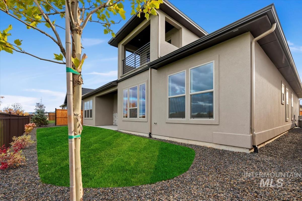 Back of house with a fenced backyard, a balcony, a patio, and stucco siding