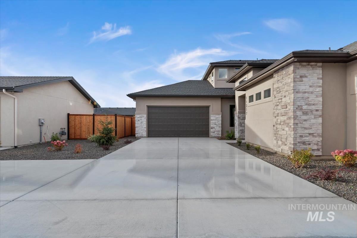 View of front of house featuring stucco siding, concrete driveway, and stone siding