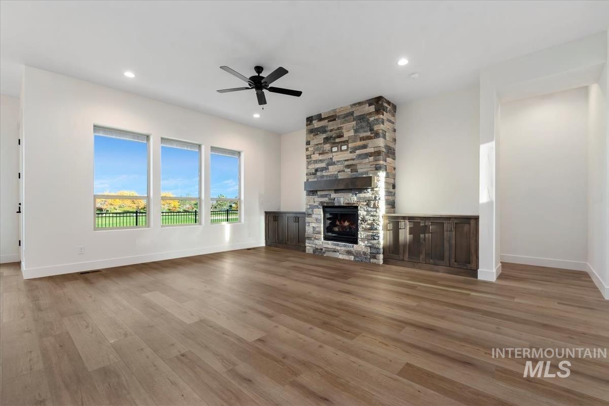 Unfurnished living room featuring light wood-style floors, a stone fireplace, recessed lighting, and a ceiling fan