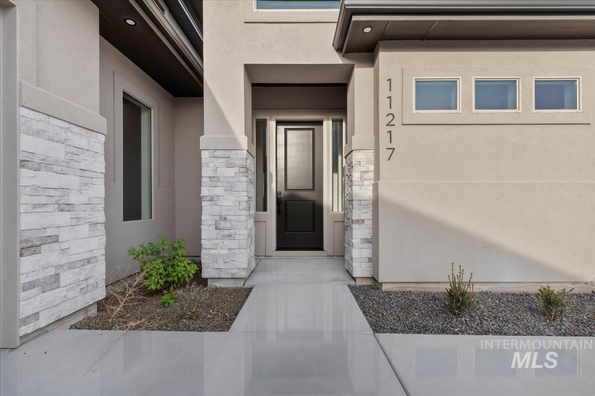 Doorway to property featuring stone siding and stucco siding