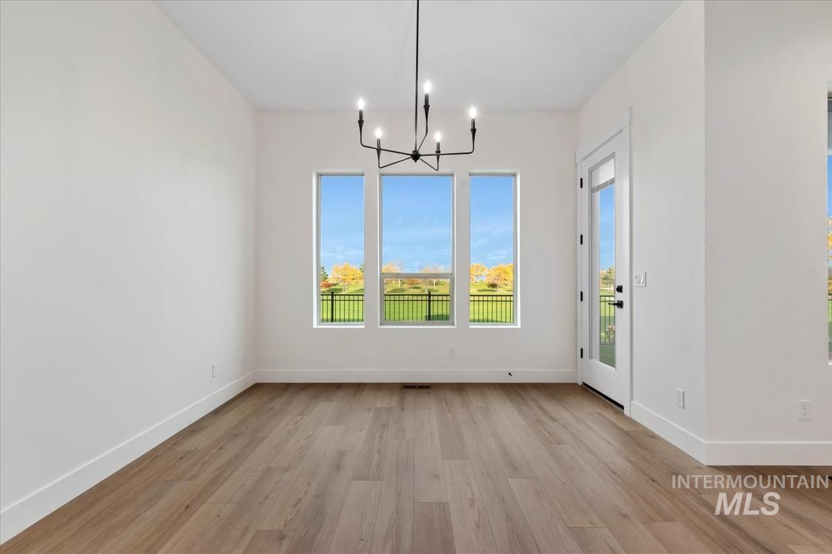 Unfurnished dining area with a chandelier and light wood-type flooring