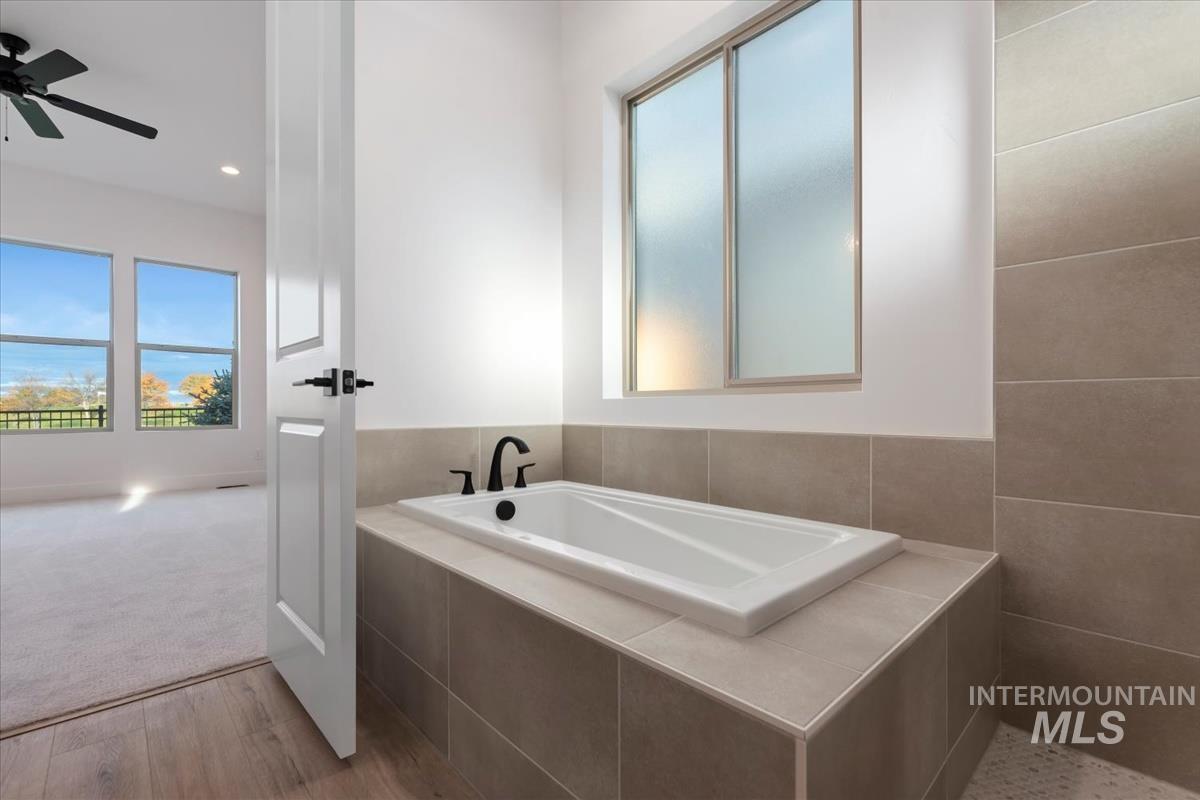 Full bathroom with a bath, light wood-type flooring, healthy amount of natural light, recessed lighting, and light carpet