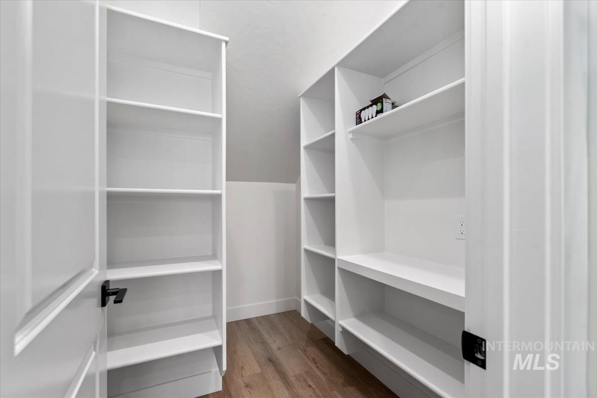 Walk in closet with dark wood finished floors