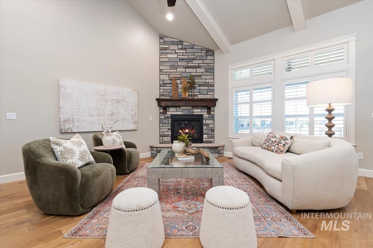 Living room with a fireplace, light wood-type flooring, and vaulted ceiling
