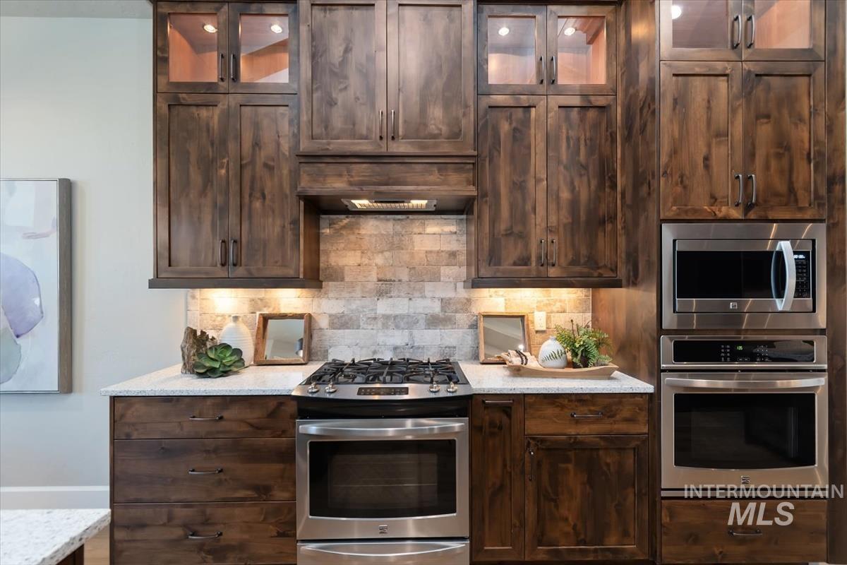 Kitchen featuring stainless steel appliances, dark wood finish cabinets, and glass fronted cabinets