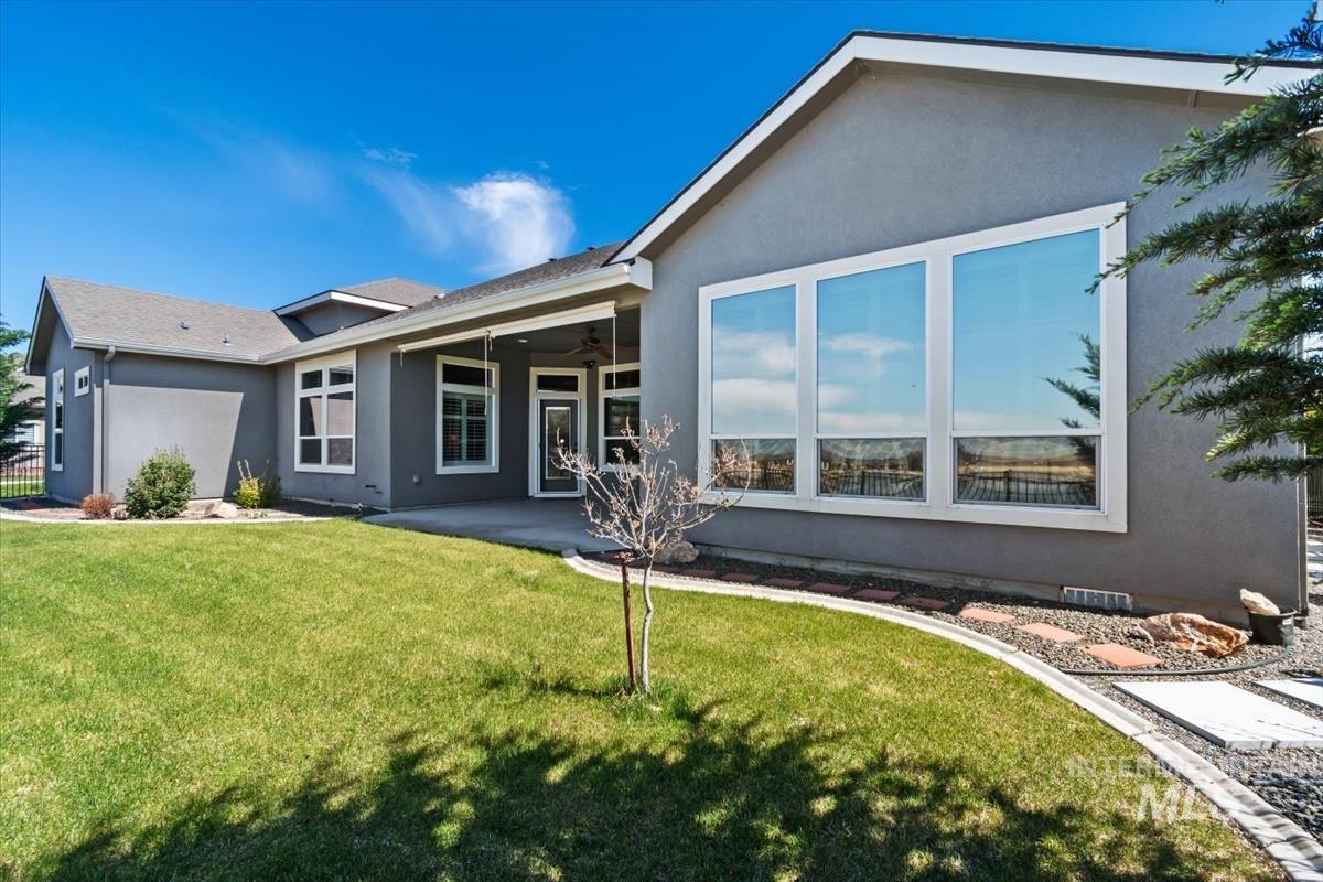 Back of property with stucco siding, a patio, a yard, and ceiling fan