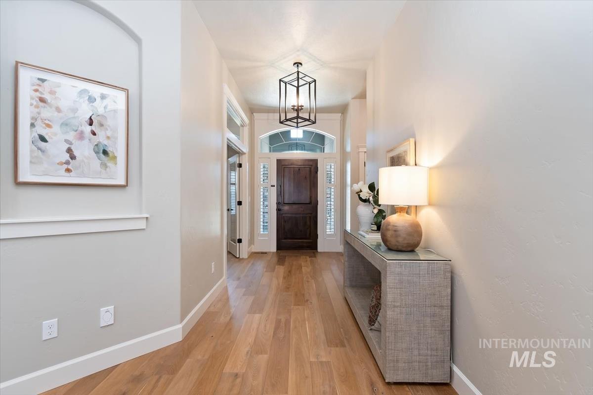 Foyer entrance with light wood-style floors and hanging lights