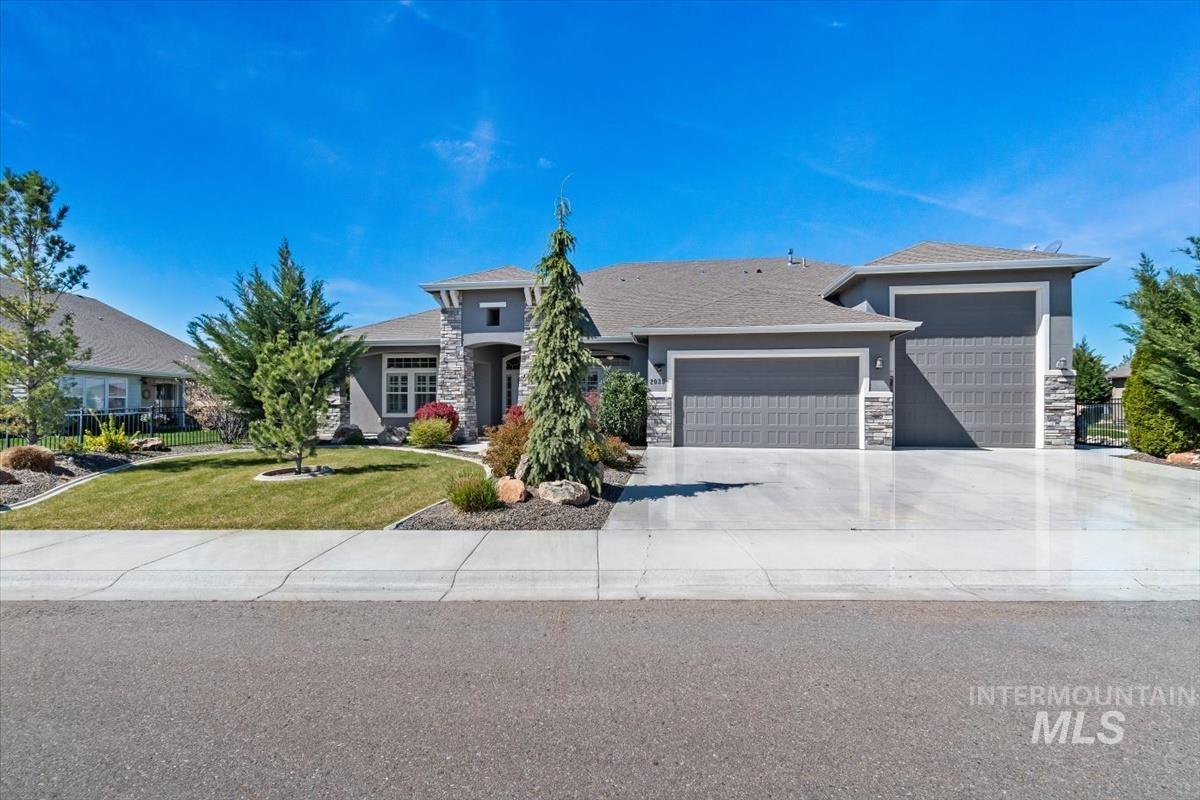 Prairie-style house with a garage, stone siding, a front lawn, and driveway