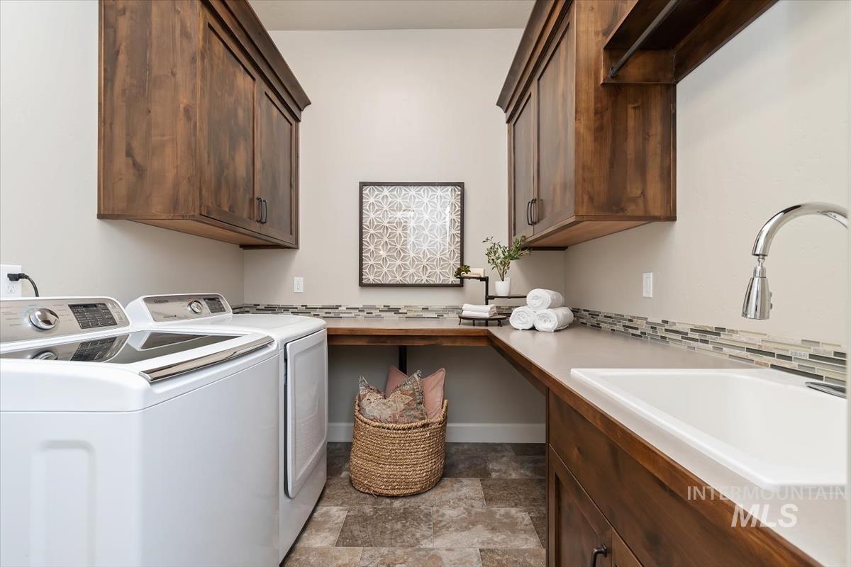 Laundry area featuring stone finish flooring, separate washer and dryer, and cabinet space