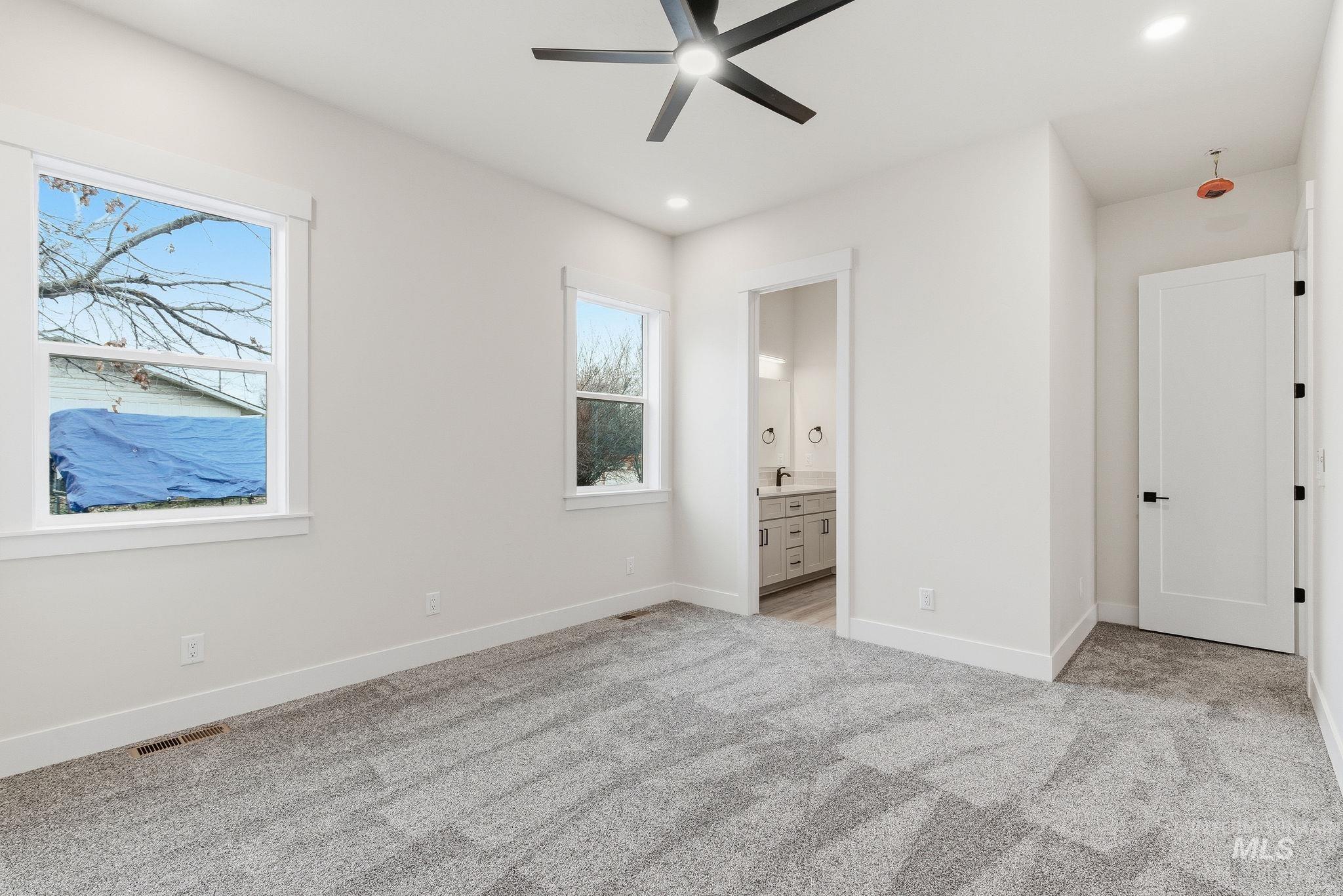 Unfurnished bedroom with connected bathroom, light carpet, ceiling fan, and recessed lighting