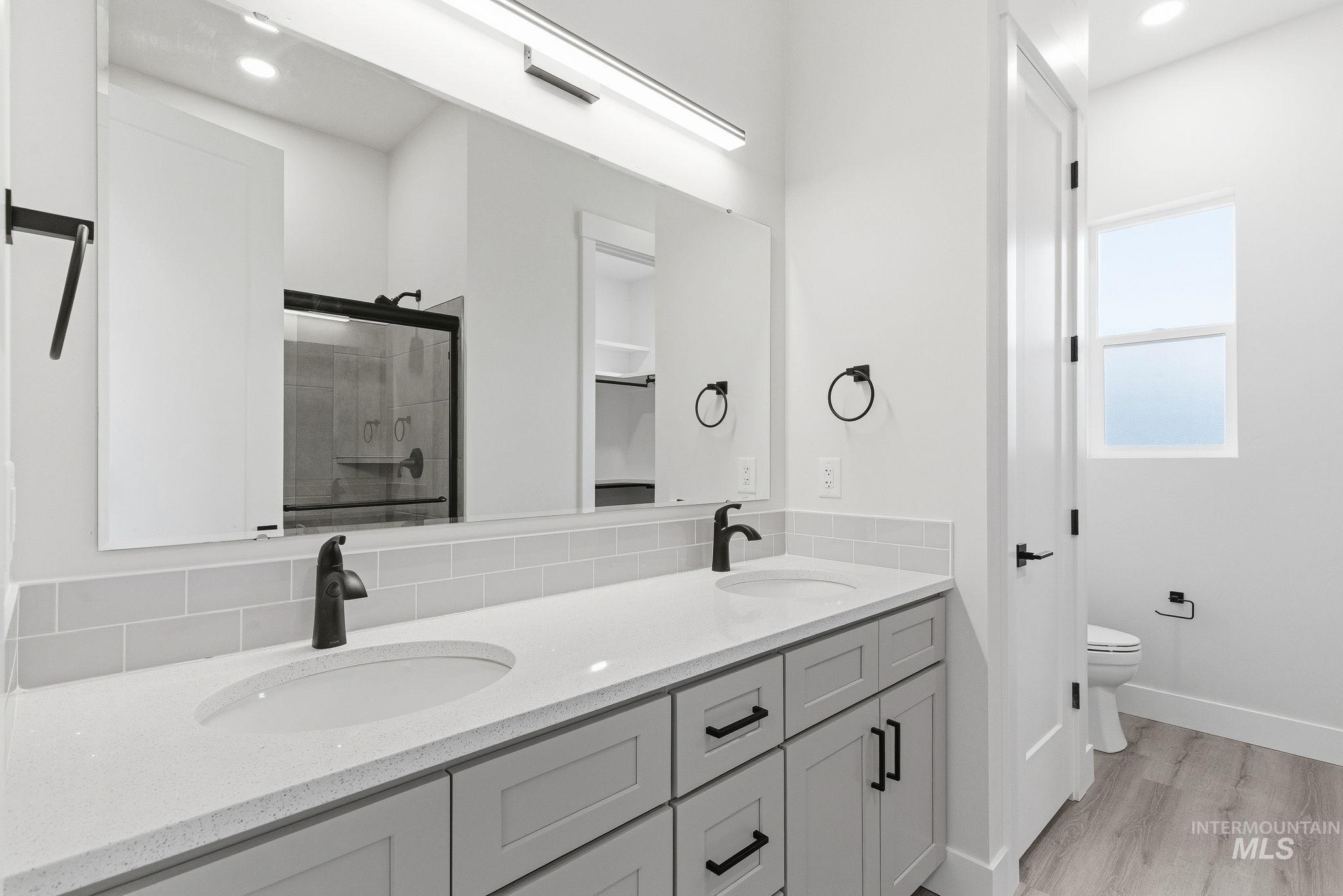 Full bath with a stall shower, double vanity, recessed lighting, and light wood finished floors
