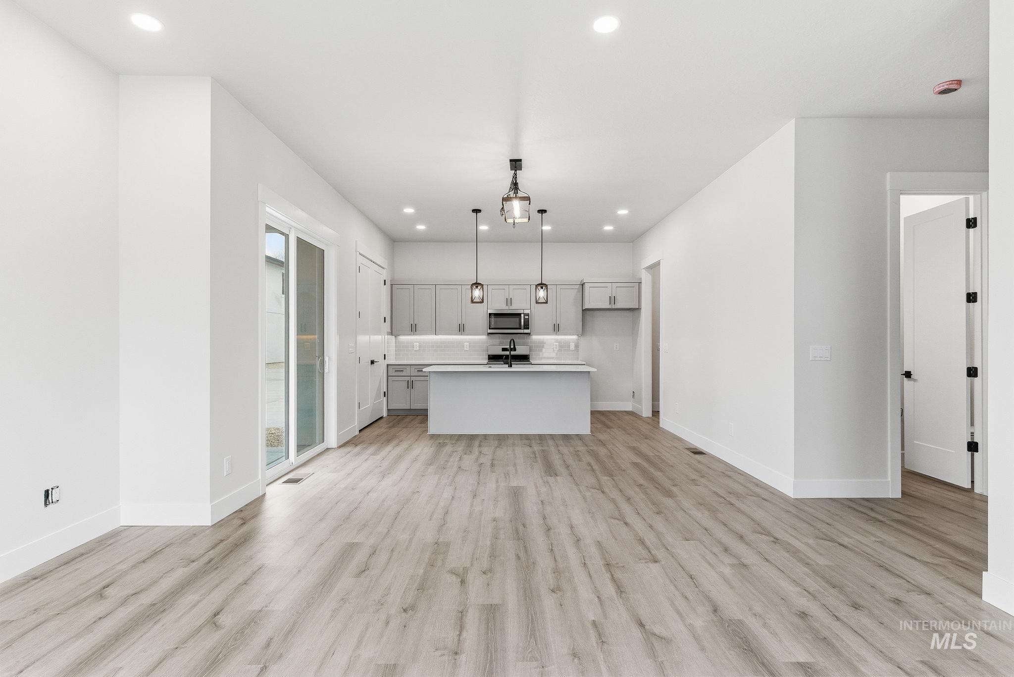 Kitchen featuring light countertops, hanging light fixtures, open floor plan, a center island, and light wood-style floors