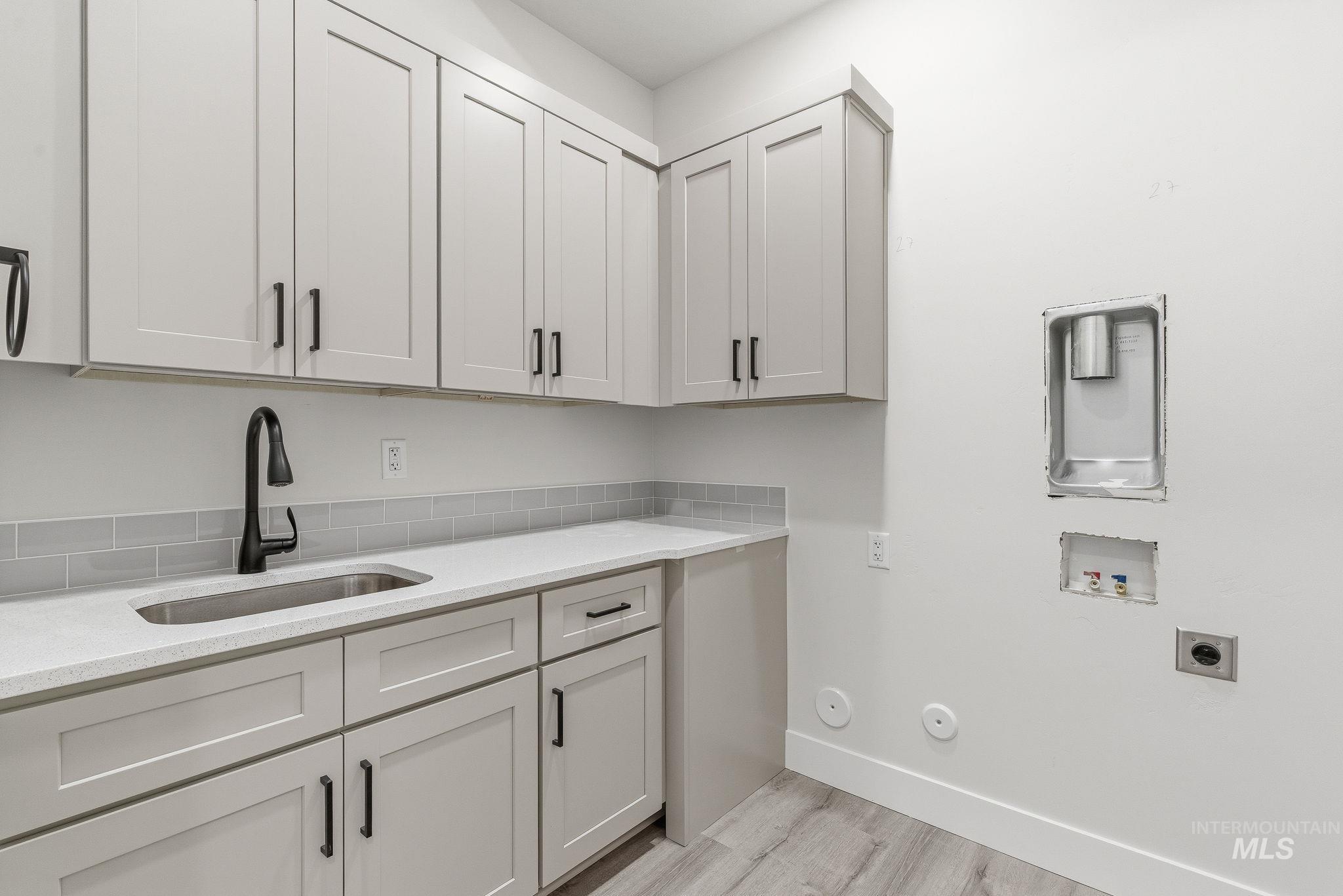 Laundry area with washer hookup, hookup for a gas dryer, light wood-style flooring, cabinet space, and electric dryer hookup