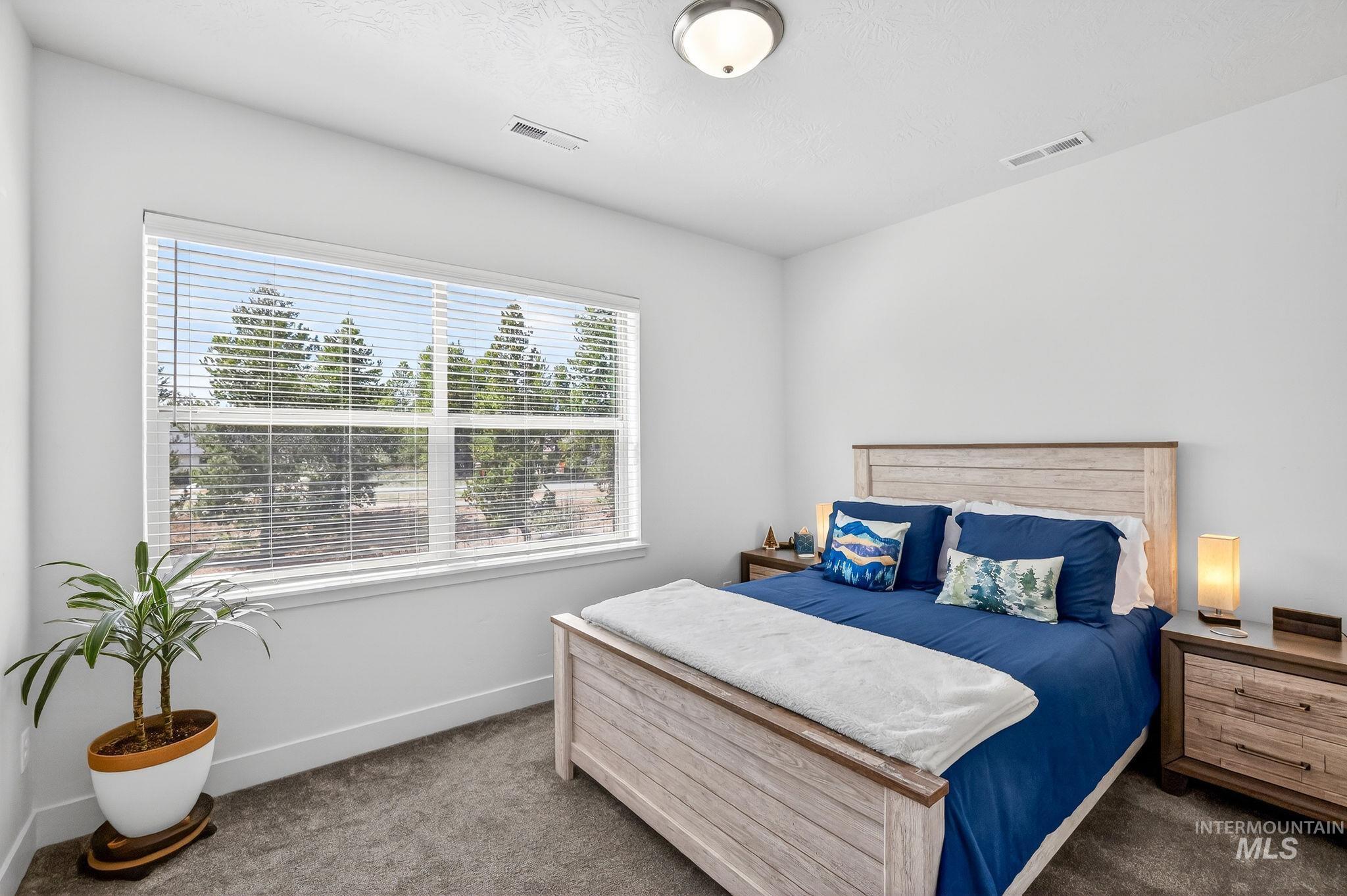Bedroom featuring a large window, neutral wall paint, ceiling-mounted light fixture, and plush carpet flooring