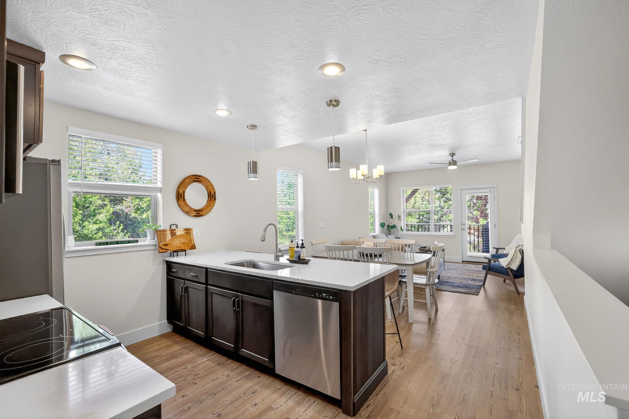 Kitchen island featuring a stainless steel sink, dishwasher, and white countertop