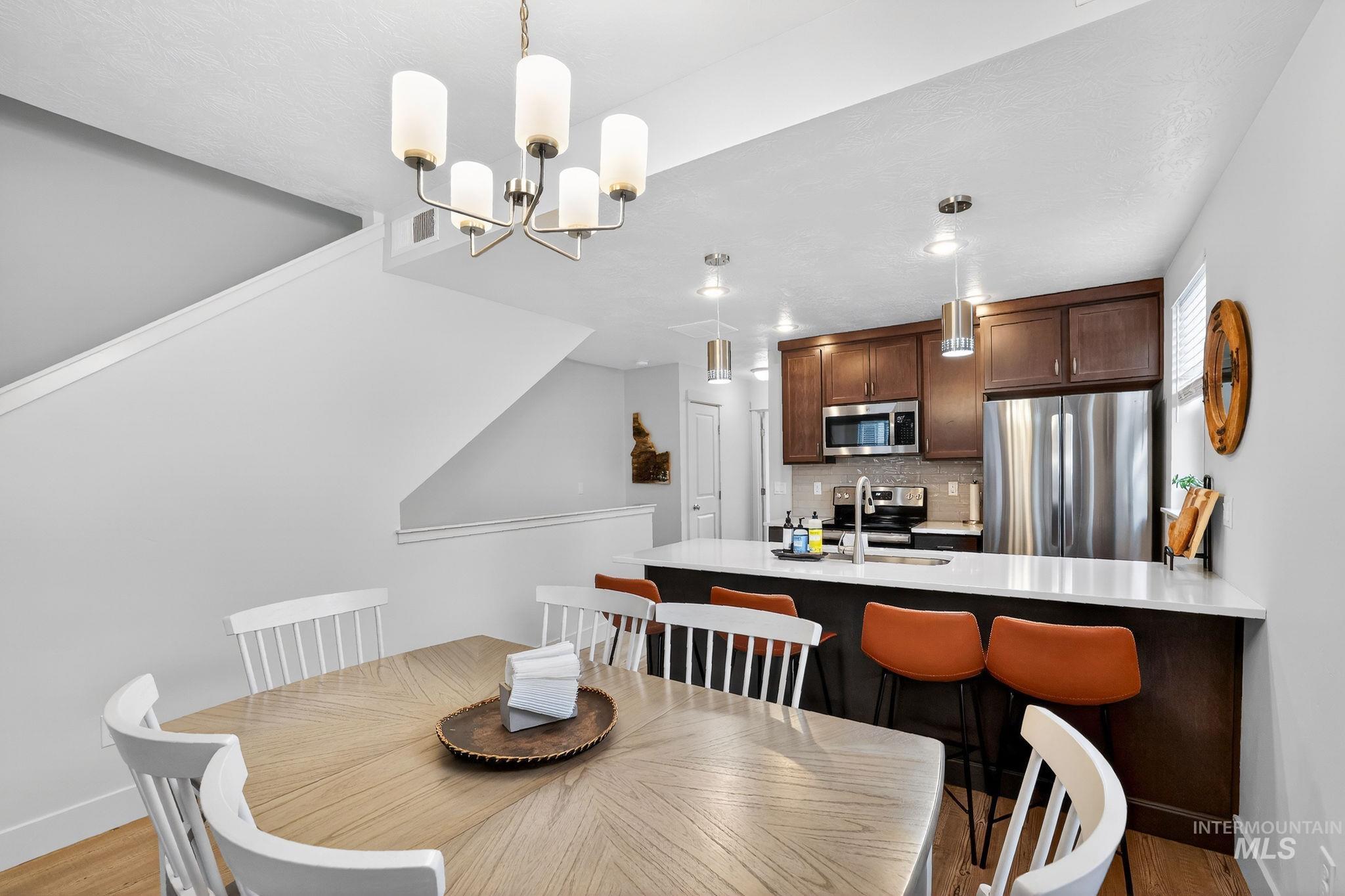 Dining area featuring a modern chandelier and wood-finish flooring