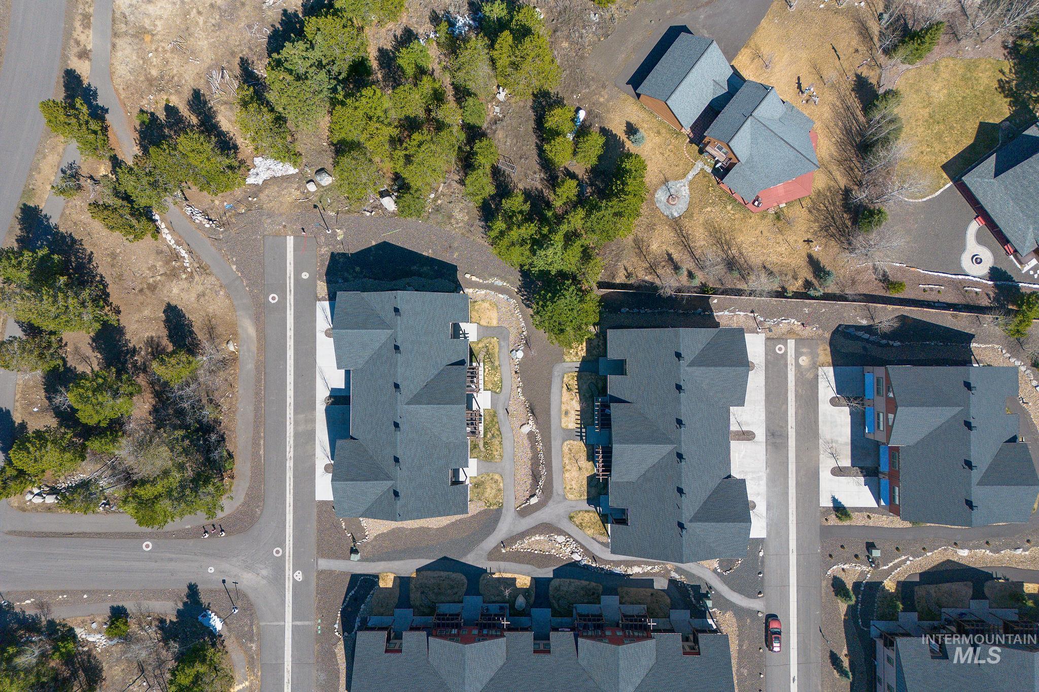 Aerial perspective showcasing multiple residential structures with dark shingled roofs and paved driveways
