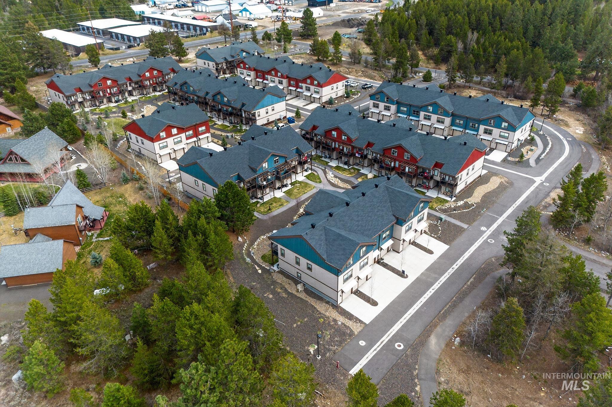 Contemporary multi-unit residential development featuring varied building colors, dark shingle roofing, and paved roadways