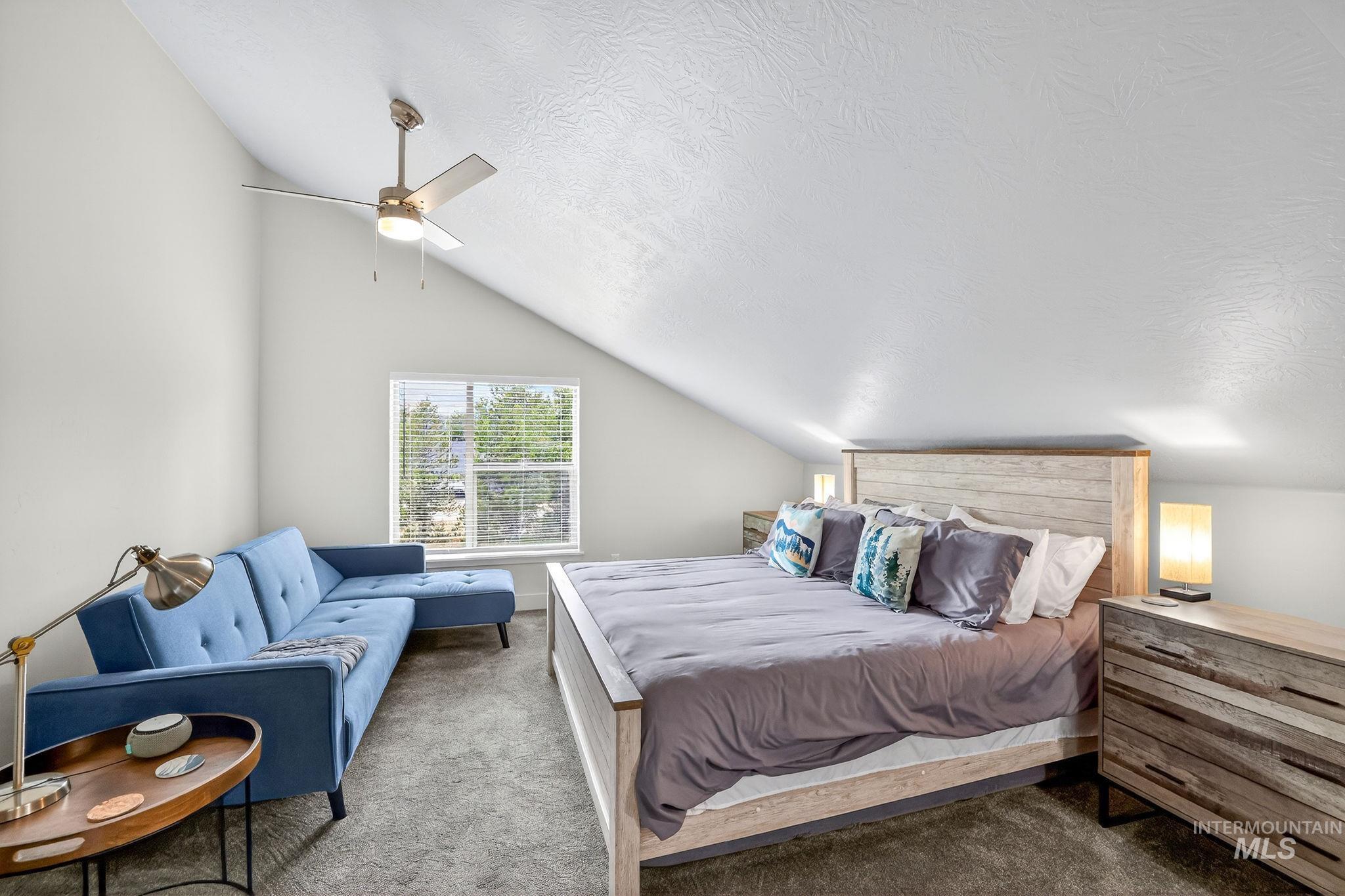 Attic bedroom featuring a sloped ceiling, recessed window with blinds, and a built-in ceiling fan with lighting