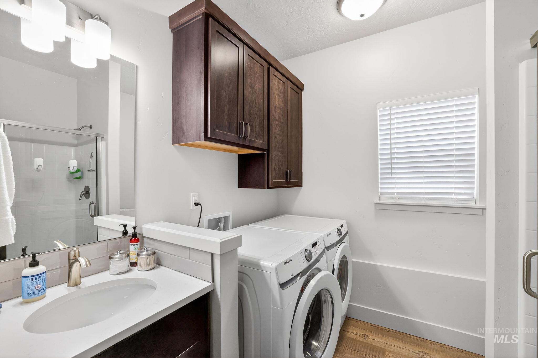 Combination bathroom and laundry area featuring a white countertop vanity with an undermount sink, brushed nickel faucet, and a large wall mirror