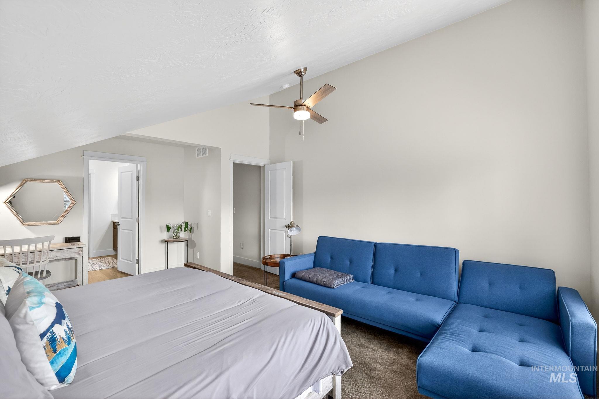 Vaulted ceiling bedroom featuring an exposed beam, ceiling fan, and access to an additional room