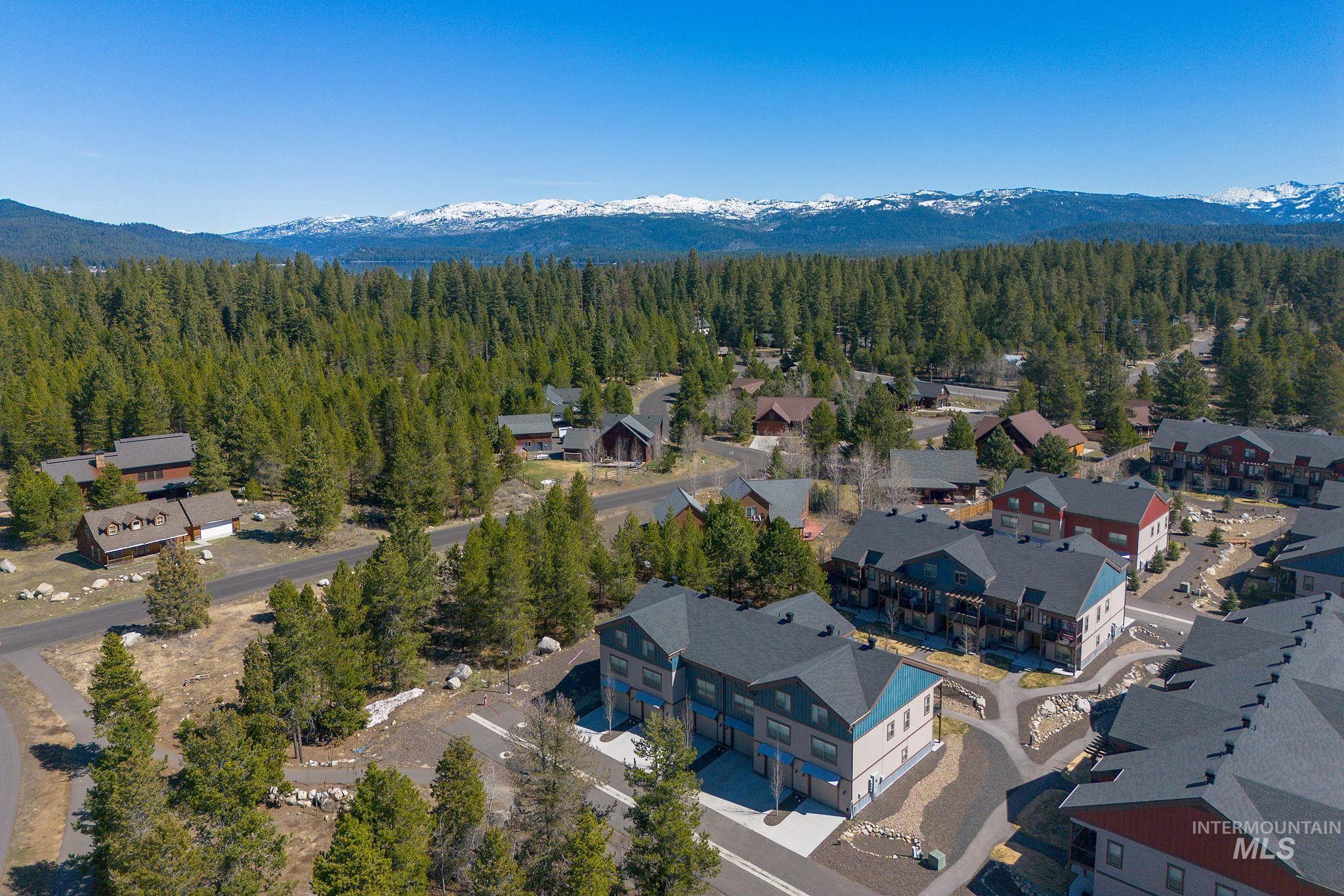 Residential community featuring a mix of single-family homes and multi-story buildings, surrounded by dense evergreen forests and paved roadways