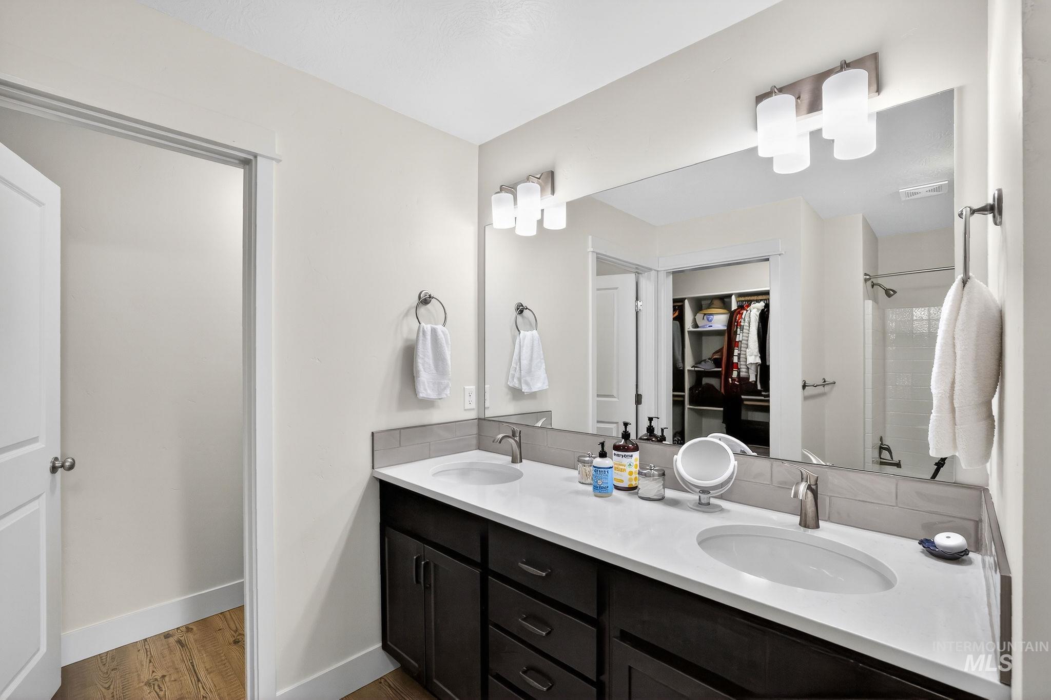 Double vanity featuring undermount sinks, white countertops, and dark wood cabinetry