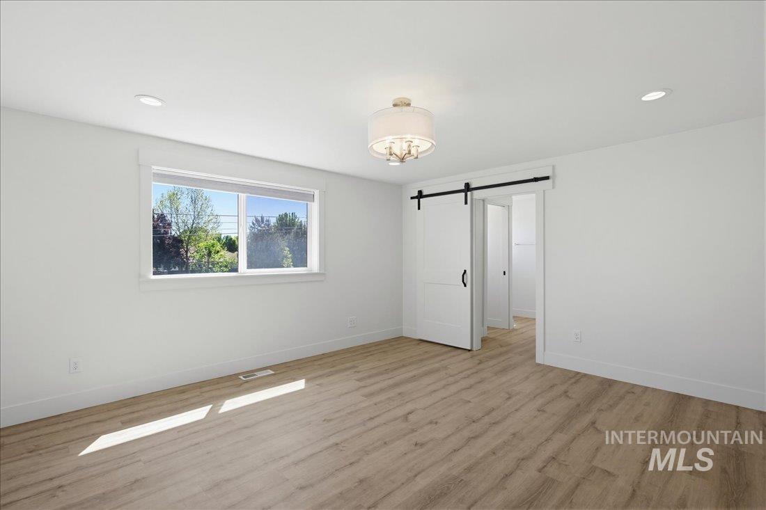 Spacious room featuring wood-finish flooring, white walls, and a large window