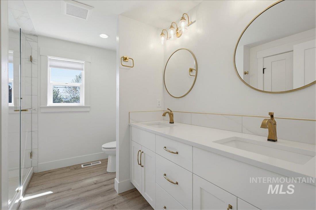 Dual vanity with white cabinetry, integrated sinks, gold-finish hardware, and round mirrors