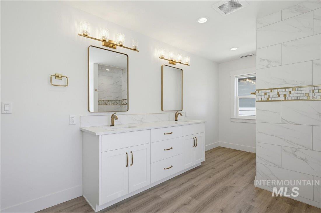 Double vanity with white cabinetry, gold-finish hardware, and a light-toned countertop