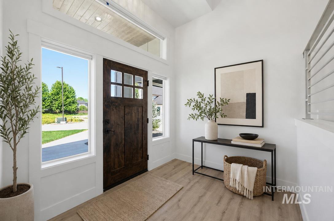 Inviting entryway featuring a dark wood-paneled door with glass inserts, flanked by large side windows, and topped with a transom window