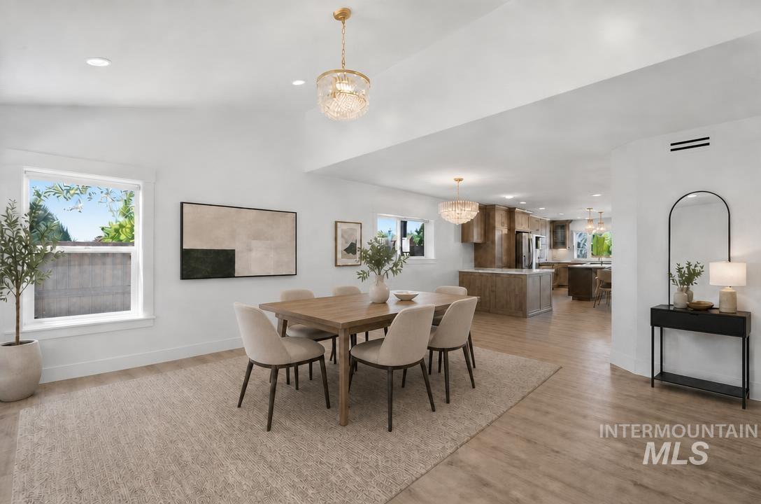 Spacious dining area featuring wood-finish flooring, recessed lighting, and a decorative chandelier