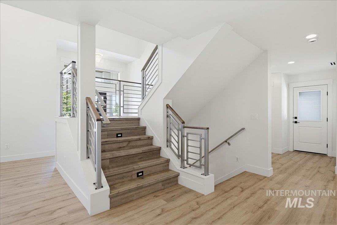 Modern staircase with wood-finish treads and risers, featuring contemporary metal railings with wood top rails