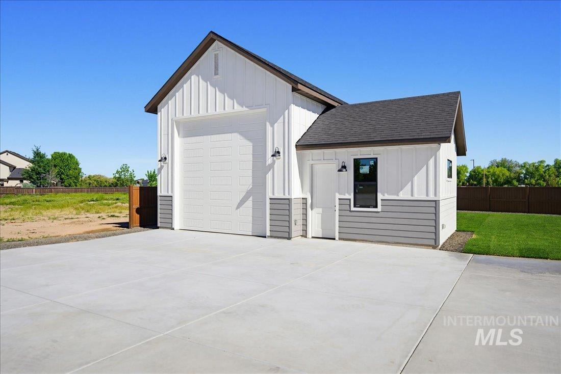 Detached structure featuring a large overhead garage door, board and batten siding, horizontal lap siding, and a side entry door