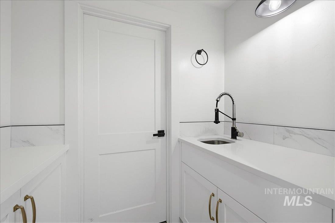Bright utility space featuring a deep stainless steel sink, a modern black pull-down faucet, and white countertops